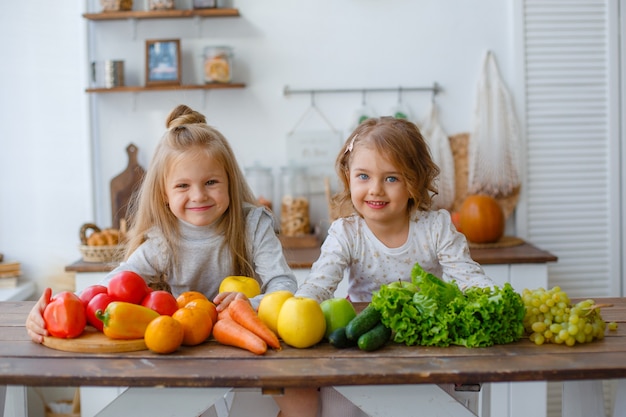 Dos niñas en la cocina con verduras en casa