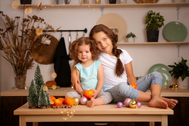 Dos niñas comiendo mandarinas en la cocina de Navidad