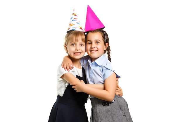 Dos niñas de cumpleaños en camisa azul uniforme escolar vestidos sombrero aislado sobre fondo blanco retrato de estudio de niños. Concepto de estilo de vida educativo para niños de la infancia. Simulacros de espacio de copia