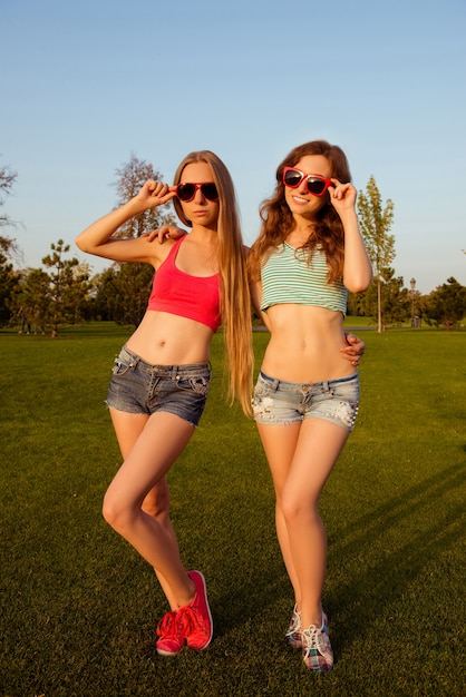 Dos niñas delgadas sosteniendo vasos en el parque