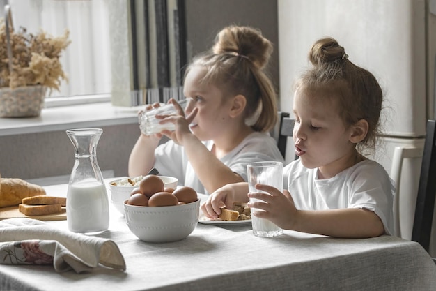 Dos niñas desayunan en casa en la cocina con productos naturales y saludables