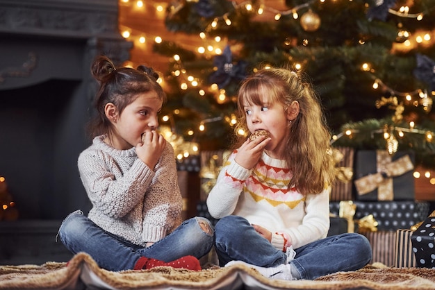 Dos niñas se divierten en una habitación decorada en navidad con cajas de regalo.