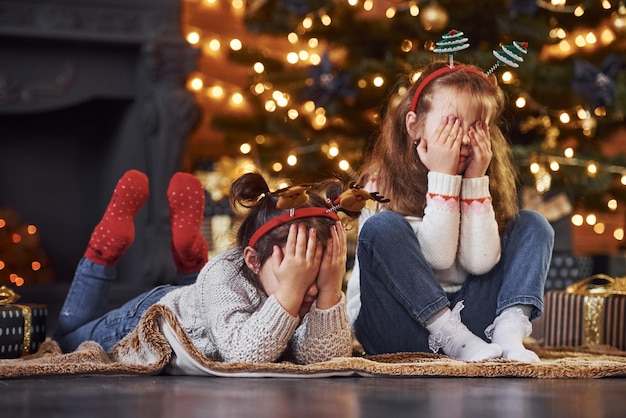 Dos niñas se divierten en una habitación decorada en navidad con cajas de regalo.