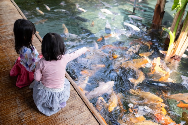 Dos niñas divirtiéndose alimentando peces koi