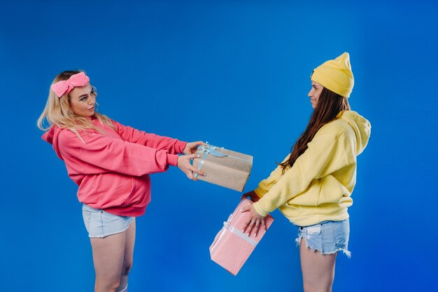 Dos niñas embarazadas con regalos en sus manos sobre un fondo azul aislado