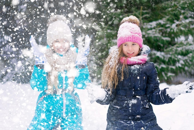 Una de las dos niñas está vomitando nieve en el parque de invierno