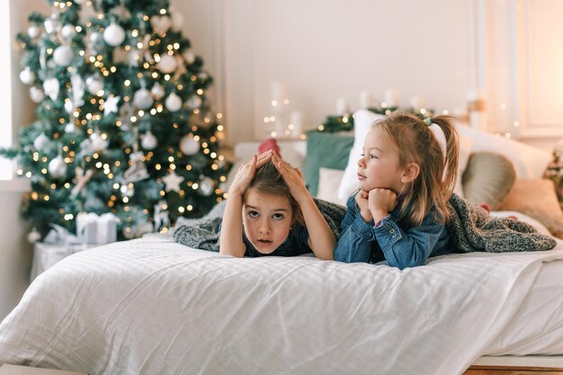 Dos niñas están acostadas en la cama en el interior del dormitorio de Navidad. la víspera de las vacaciones