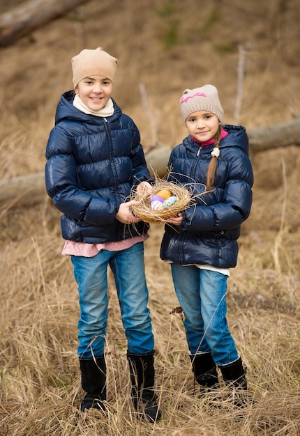 Dos niñas felices en búsqueda de huevos de Pascua en el bosque