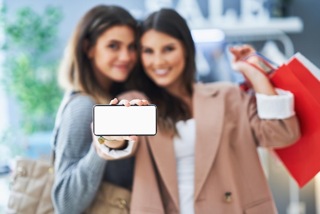 Foto dos niñas felices en compras sosteniendo el teléfono. foto de alta calidad
