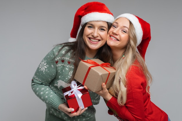 Dos niñas felices con gorros de santa con gifta celebrando navidad y año nuevo.