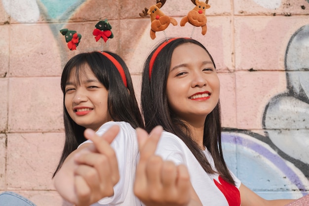 Foto dos niñas felices usan sombrero de navidad sobre fondo de colores.