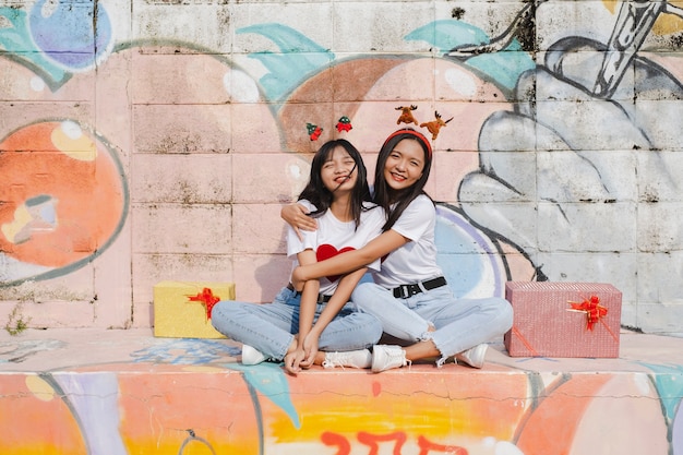 Dos niñas felices usan sombrero de Navidad sobre fondo de colores.