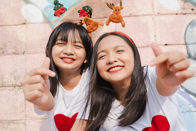 Dos niñas felices usan sombrero de Navidad sobre fondo de colores.