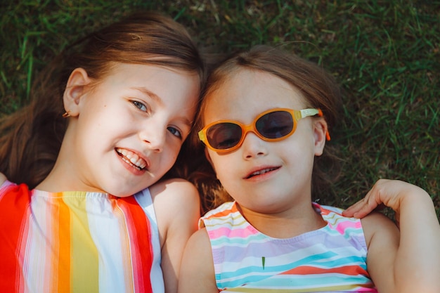 Dos niñas hermosas yacen en la hierba verde en una vista superior del parque de veranoniño con síndrome de down