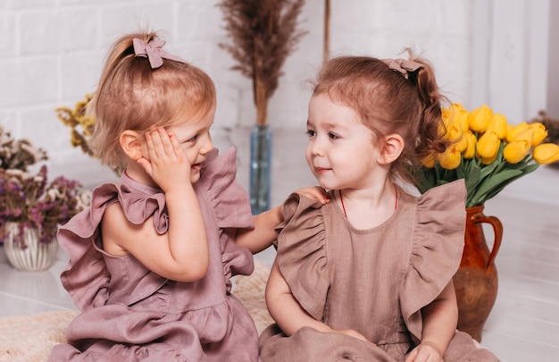 Dos niñas con hermosos vestidos en el estudio con flores.