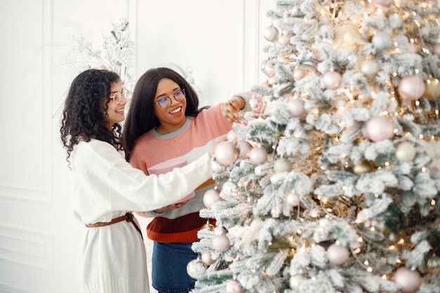 Dos niñas indias con anteojos decorando el árbol de Navidad