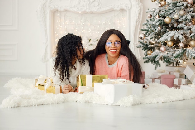 Dos niñas indias con anteojos yacían en el suelo cerca del árbol de Navidad