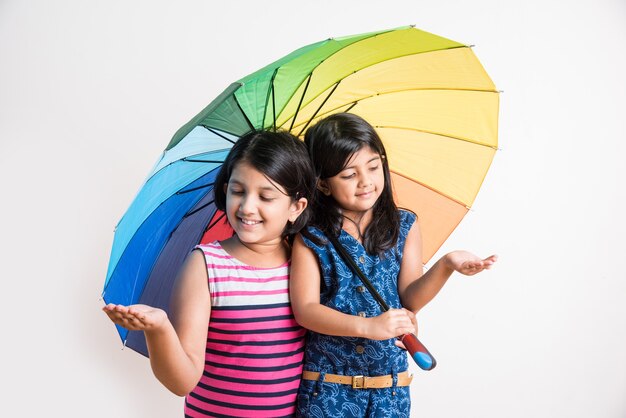 Dos niñas indias con paraguas de colores, aislado sobre blanco