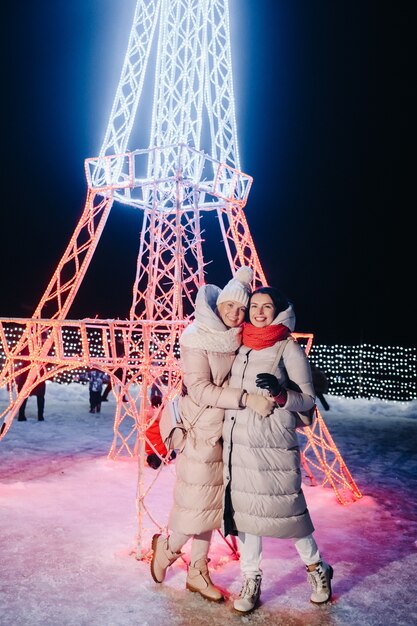 Dos niñas en invierno con luces de Nochevieja encendidas en la calle de Navidad