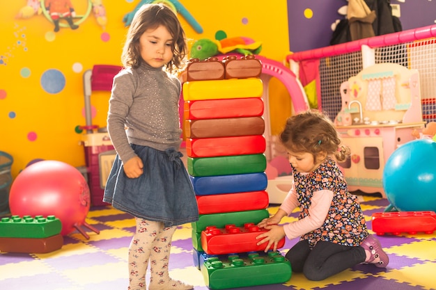 Dos niñas juegan con ladrillos grandes en la sala de juegos.