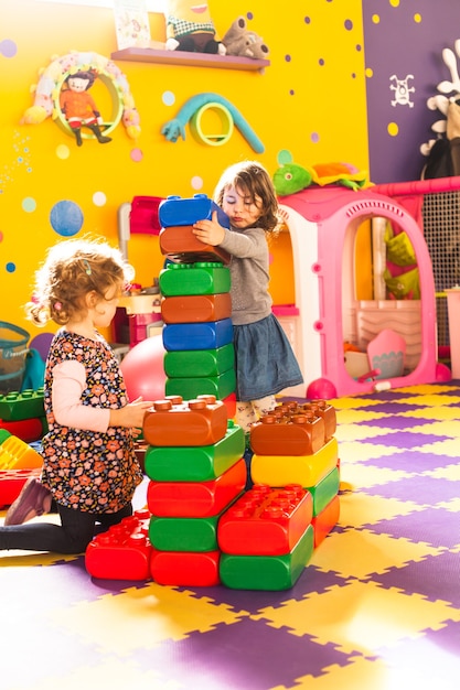 Dos niñas juegan con ladrillos grandes en la sala de juegos.