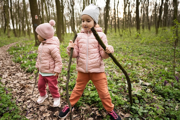 Dos niñas jugando con palos en el bosque de primavera