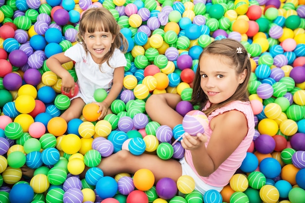 Dos niñas jugando en la piscina con pelotas de plástico