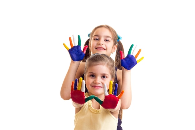 Dos niñas lindas en camisas negras y amarillas con coletas y manos coloreadas en estudio