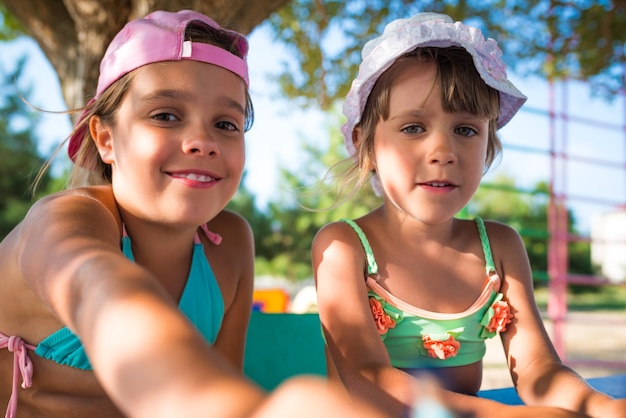 Dos niñas lindas jugando muñecas al aire libre mientras se relaja en la playa en un caluroso día de verano