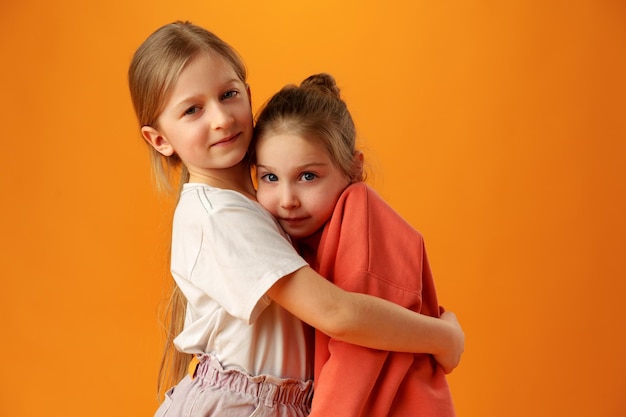 Dos niñas lindas paradas sobre fondo amarillo en el estudio