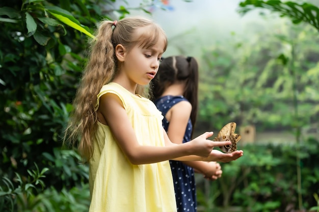 dos niñas con mariposas en un invernadero