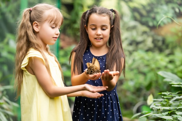 dos niñas con mariposas en un invernadero