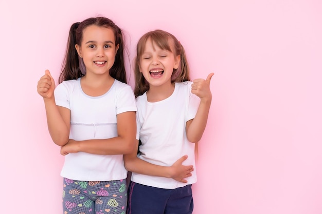 Foto dos niñas - mejores amigas, aisladas sobre un fondo rosa