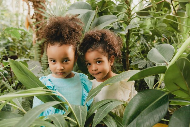 Dos niñas morenas y sonrientes con vestidos de lino caminan por el jardín retrato de dos mujeres de piel oscura