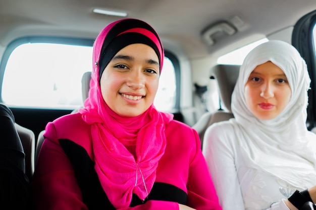 dos niñas musulmanas felices en un automóvil que va en un viaje