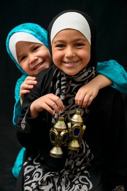 Foto dos niñas musulmanas felices con linterna de ramadán sobre fondo negro