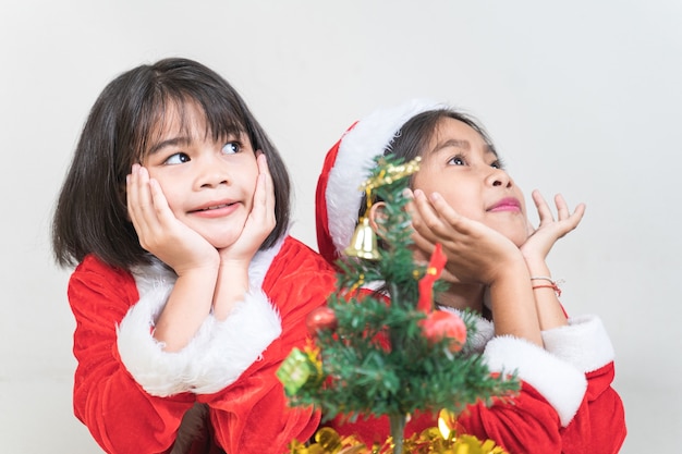 Dos niñas de niños asiáticos vistiendo traje rojo de Santa Claus para celebrar las vacaciones de Navidad en casa