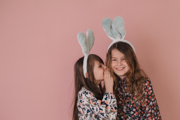 Dos niñas con orejas de conejo sosteniendo una canasta de huevos de Pascua