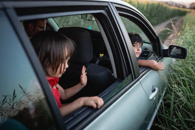 Foto dos niñas y un padre mirando desde las ventanas de los autos familiares