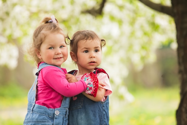 Dos niñas en el parque bajo el árbol en flor.