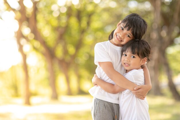 Dos niñas pequeñas asiáticas abrazándose con amor en el jardín i