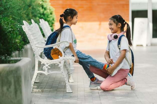 Dos niñas pequeñas sentadas en un banco en el parque y hablando