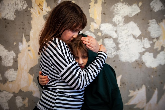 Dos niñas de pie en un abrazo en la pared destruida y concepto de miedo de las últimas noticias en el mundo sobre el ataque de Rusia a Ucrania