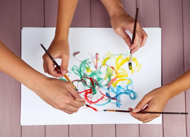 Dos niñas pintando con pincel y pinturas coloridas