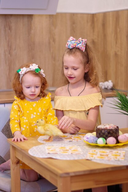 Dos niñas en Semana Santa con patitos amarillos Junto al pastel y huevos pintados Felicidad familiar de vacaciones