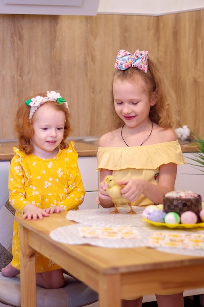 Dos niñas en Semana Santa con patitos amarillos Junto al pastel y huevos pintados Felicidad familiar de vacaciones