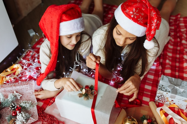 Dos niñas con sombreros de navidad empacando regalos de navidad