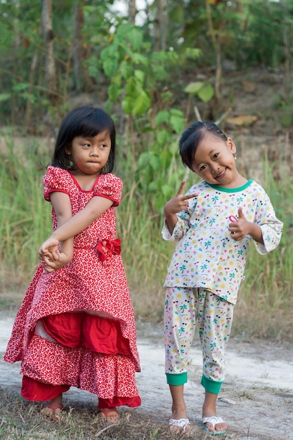 Dos niñas sonríen y una lleva un vestido rojo y blanco.