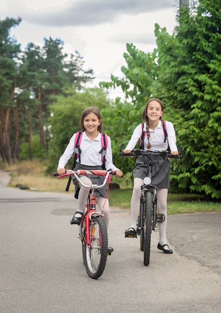 Dos niñas sonrientes en bicicleta a la escuela