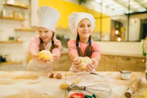 Dos niñas sonrientes cocineros en mayúsculas muestra bolas de masa